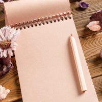 Blank notebook with flower on vintage wooden table